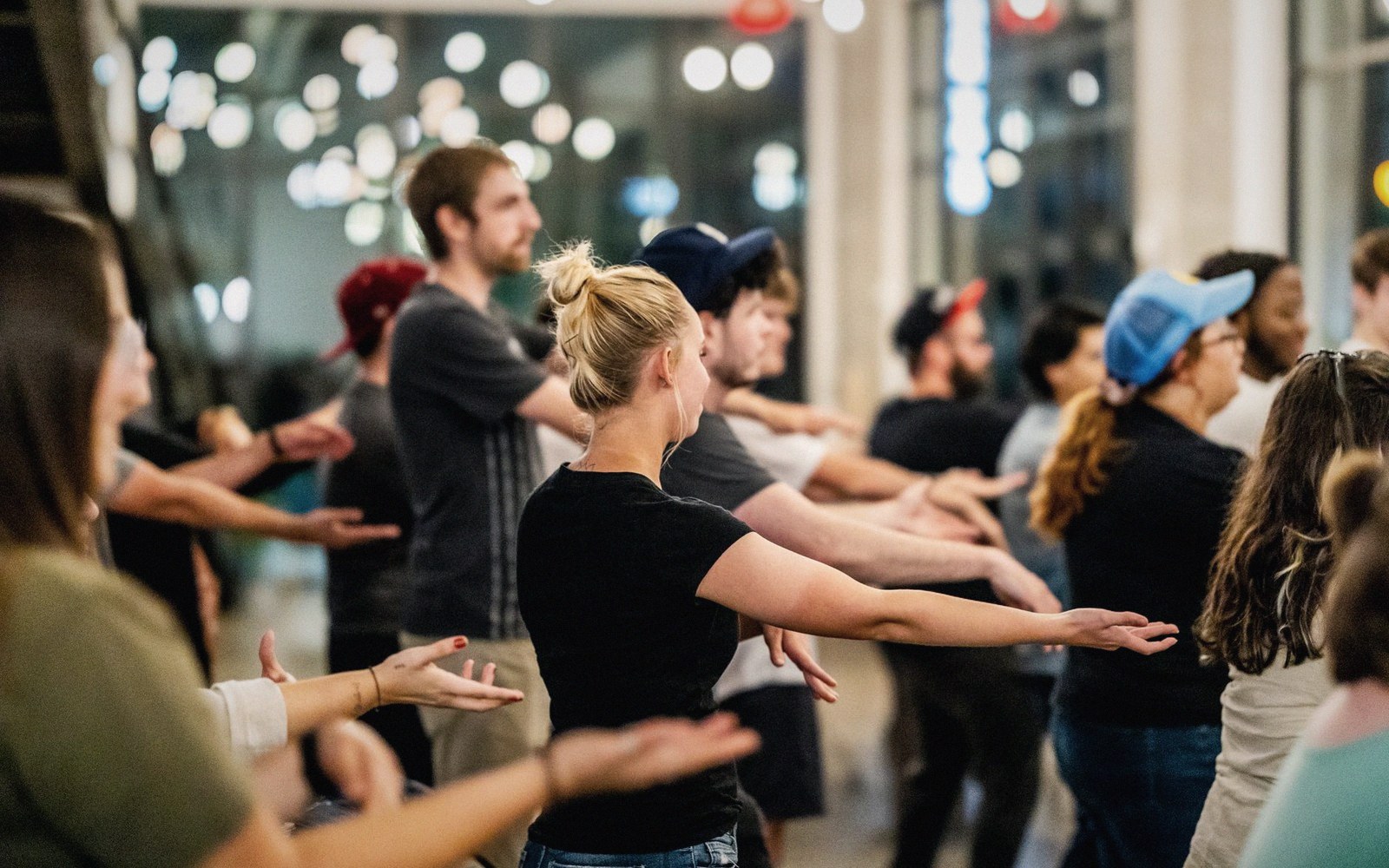 A group of people extend their arms in unison during a swing dance class