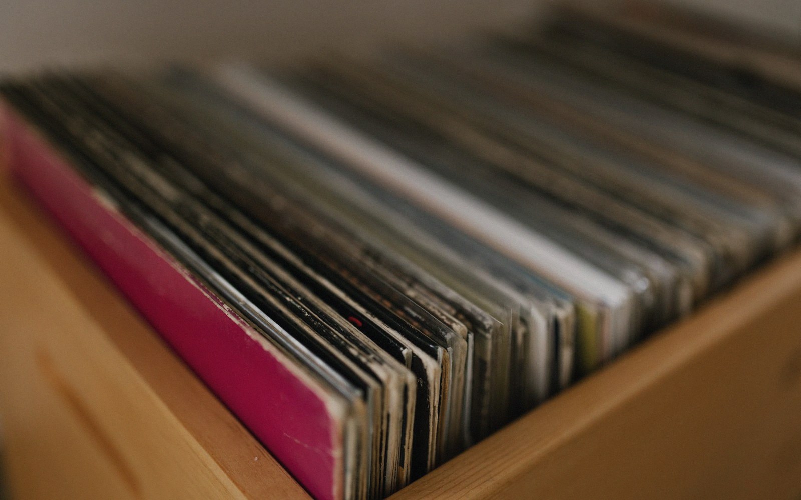 Rows of vinyl record sleeves stacked upright in a wooden crate