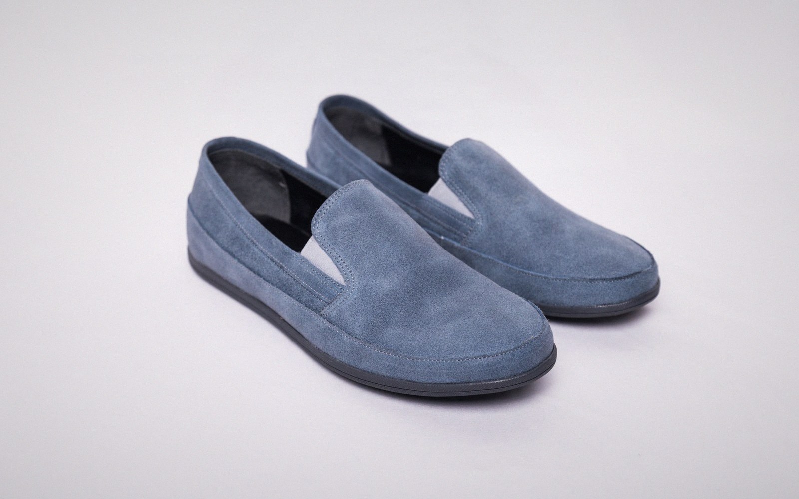 A pair of blue suede slip-on loafers with a rubber sole