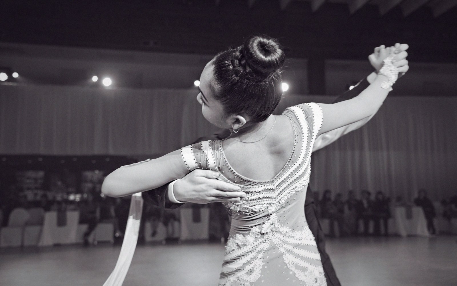 A ballroom dancer in a beaded gown poses with a partner during a competition