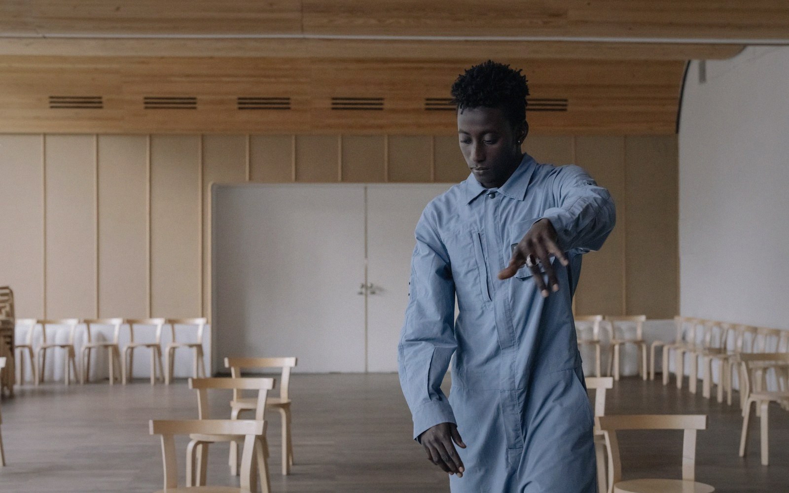 An empty dance hall with the house lights up, chairs stacked at the edge, floor swept