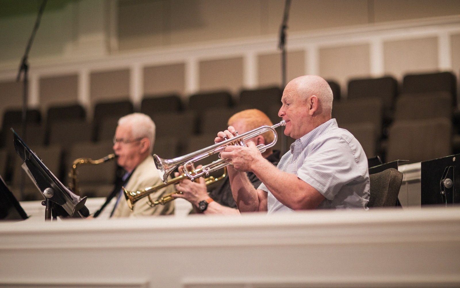 A horn section mid-phrase, instruments up, music stands lit